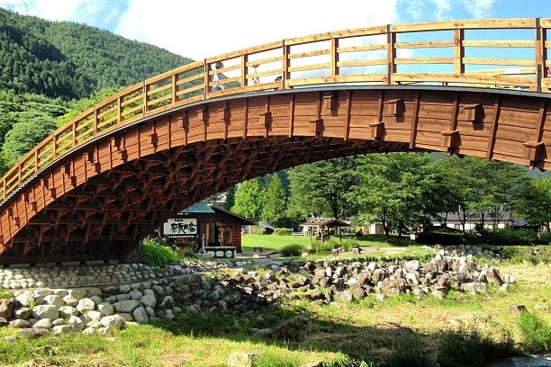 道の駅奈良井木曽の大橋の真ん中を奈良井川の清流が流れ、そこにかかる美しい樹齢300年以上の総檜作りの太鼓橋は橋脚を持たない木製の橋としては日本有数の大きさ。橋の下部の木組からは匠の技を垣間見ることができ、日没後のライトアップされた姿は幻想的です。 今月は