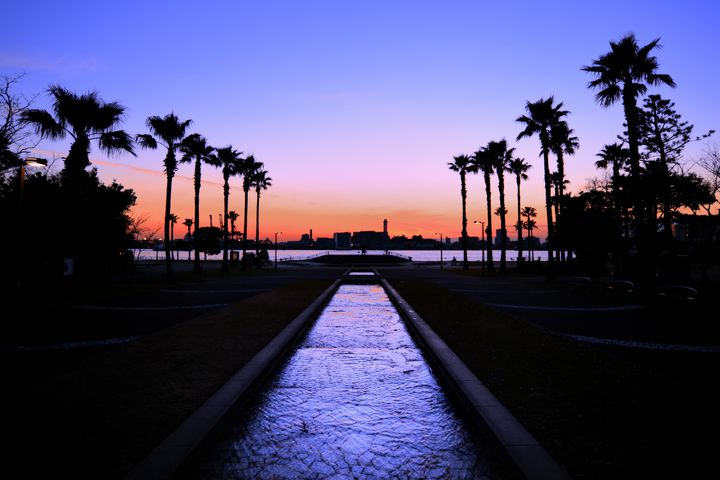 お台場海浜公園から臨む沈む夕日と飛行機と明かりのついた屋形船GANREF